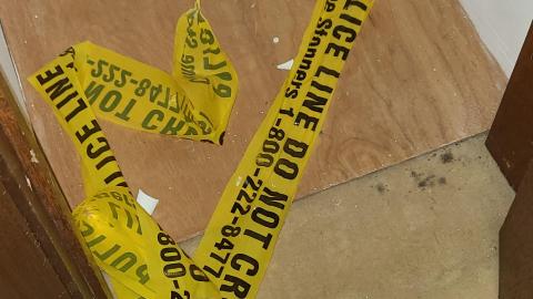 Crime scene tape on the floor inside House 2