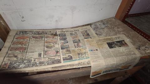 Newspapers on a shelf inside basement of House 2