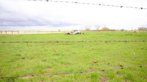Old car behind barbed wire fence