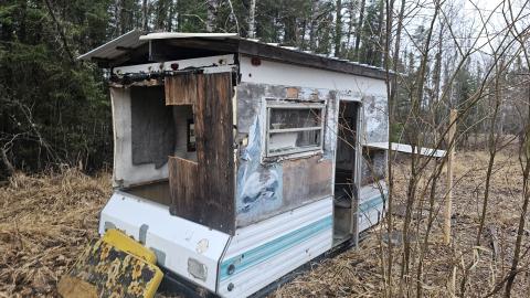An old tent trailer modified with solid walls and a roof