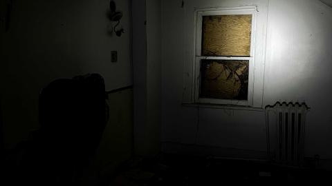 an empty room in an abandoned house with a spotlight pointing at a boarded-up window