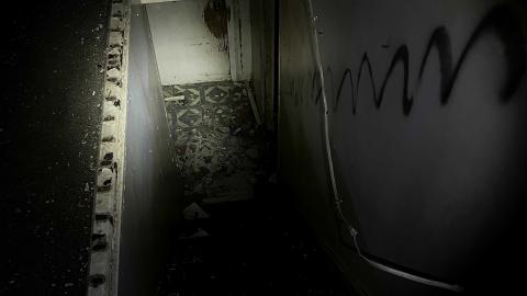 a stairwell in an abandoned house with debris on the floor and a graffiti scribbled on the wall