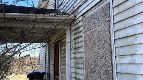 the front of an abandoned house with its windows boarded up