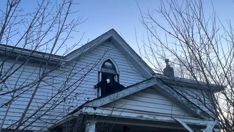 a man leaning out of the window of an abandoned house