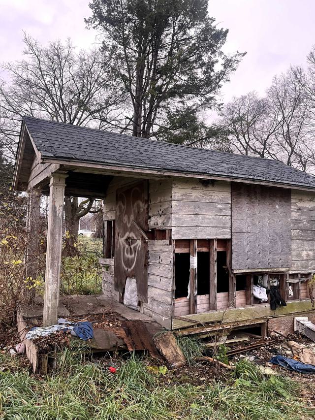 an abandoned small shed with graffiti and trash lying around