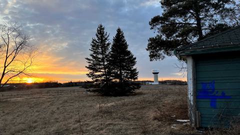a big field at sunset with a water tower