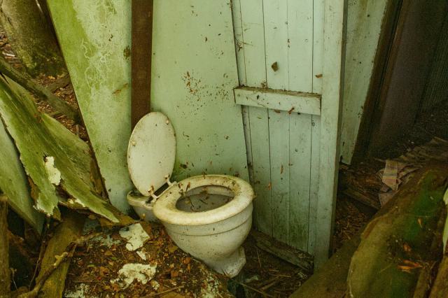Porcelain outhouse toilet sinking into the floor.
